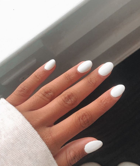 Dłoń z białym manicure hybrydowym